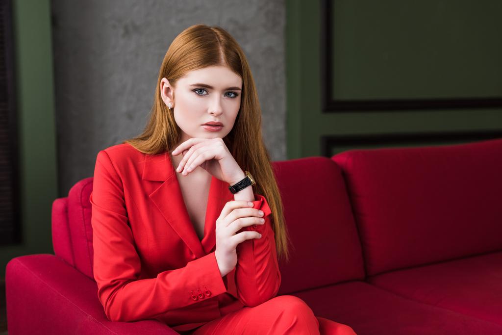 Portrait de jeune modèle féminin avec montre-bracelet assise sur le canapé
 - Photo, image