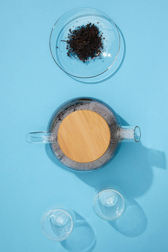 Widok góry czajnik herbata, pustej szklanki i suchej herbaty ziołowej w misce na niebiesko  - Zdjęcie, obraz