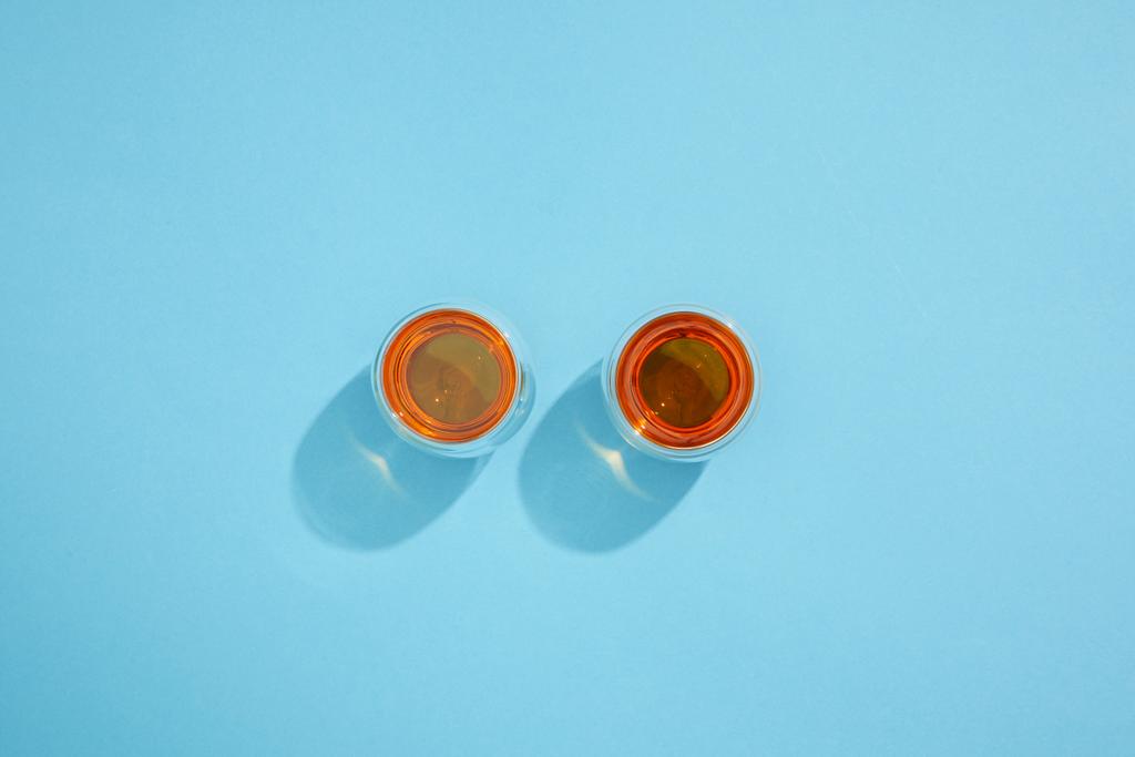 pohled shora poháry s čerstvým horký čaj a stíny na modré  - Fotografie, Obrázek