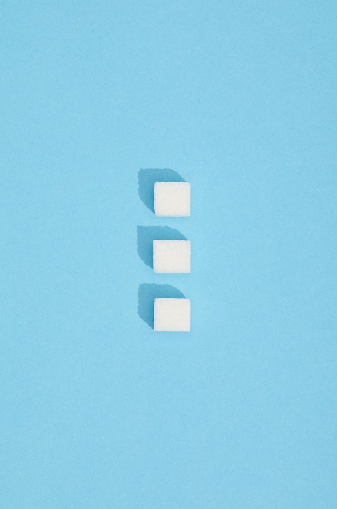 sweet white sugar cubes with shadows on blue  - Photo, Image