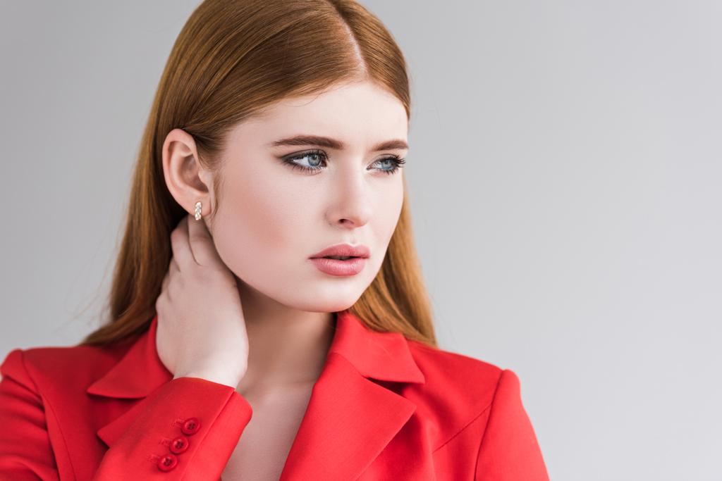 Portrait of young female fashion model with earrings in jacket isolated on grey - Photo, Image
