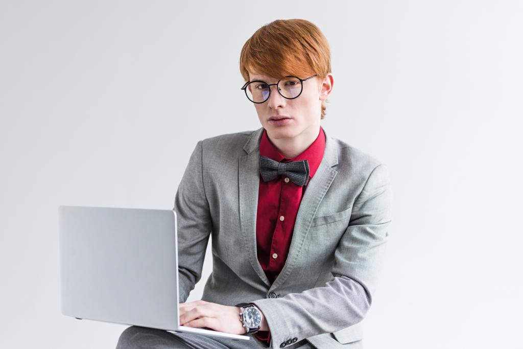 Молодой мужчина модель в очках с помощью ноутбука, изолированного на сером
 - Фото, изображение