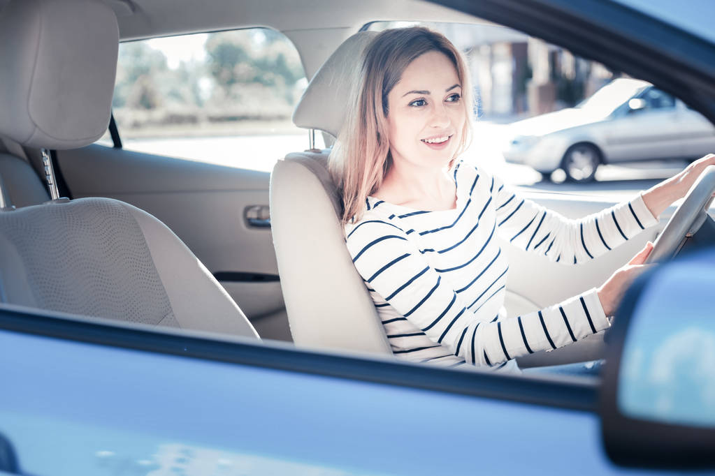 Zadowolony ładna kobieta uśmiechając się i jazda w samochodzie. - Zdjęcie, obraz