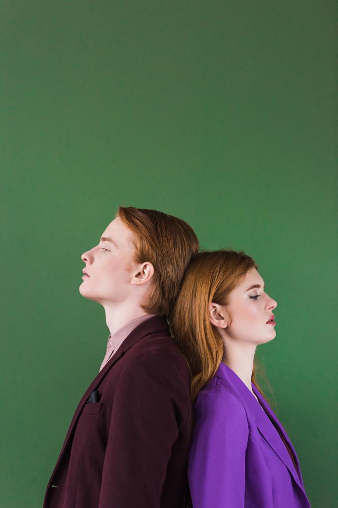 Μερική άποψη του το κομψό ζευγάρι των μοντέλων που στέκεται πλάτη με πλάτη απομονώνονται σε πράσινο - Φωτογραφία, εικόνα