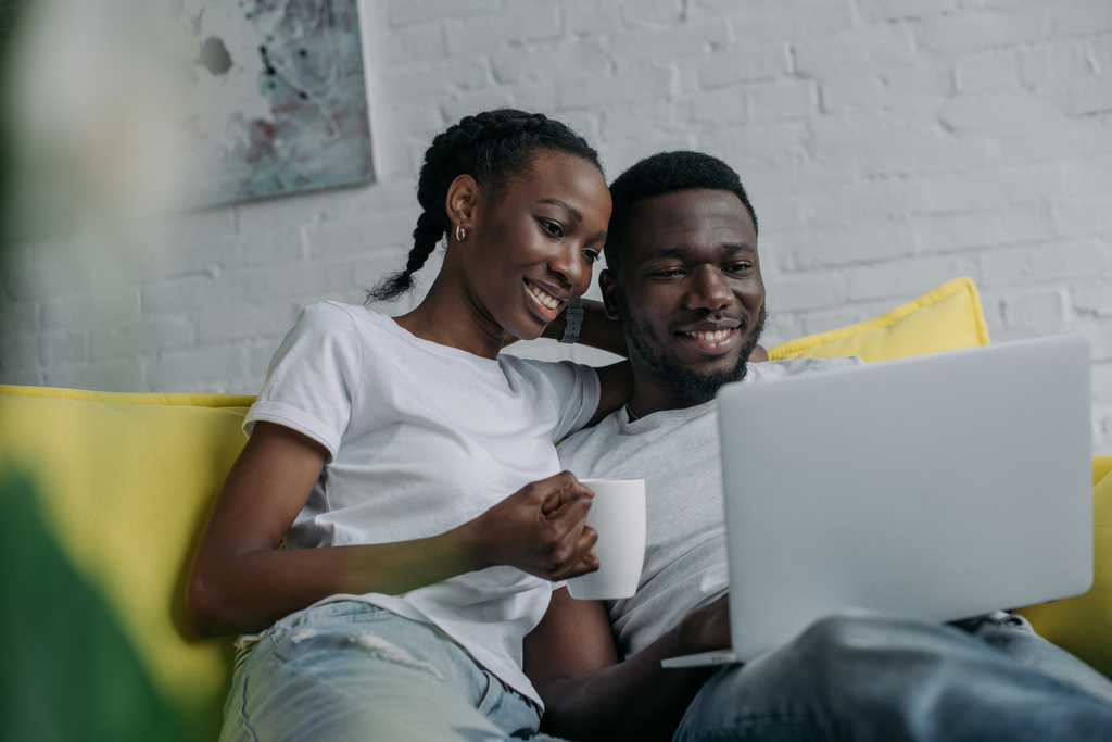 Szczęśliwa Młoda para african american komputera przenośnego razem w domu  - Zdjęcie, obraz