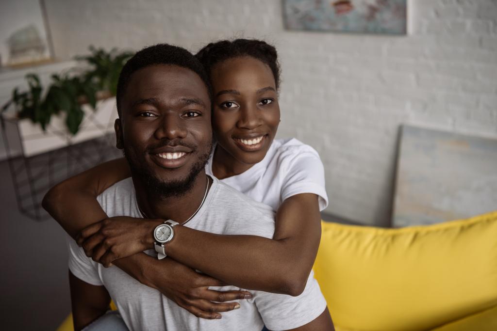 mutlu genç Afro-Amerikan çifte sarılma ve kameraya gülümseyen - Fotoğraf, Görsel