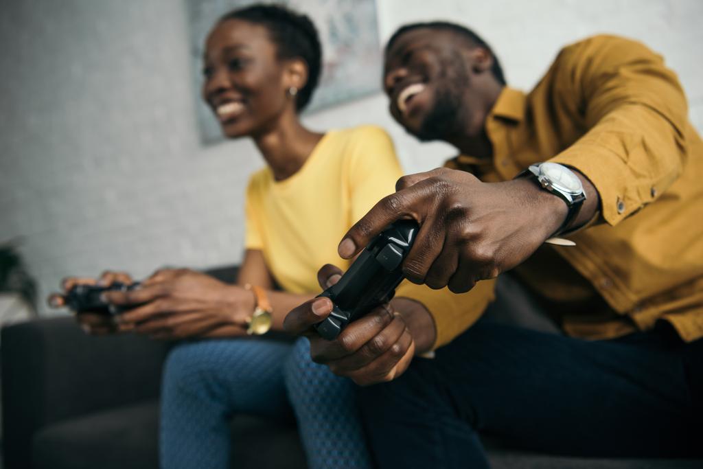 χαρούμενος νεαρός αφρικανική αμερικανική ζευγάρι παίζει με χειριστήρια μαζί στο σπίτι - Φωτογραφία, εικόνα