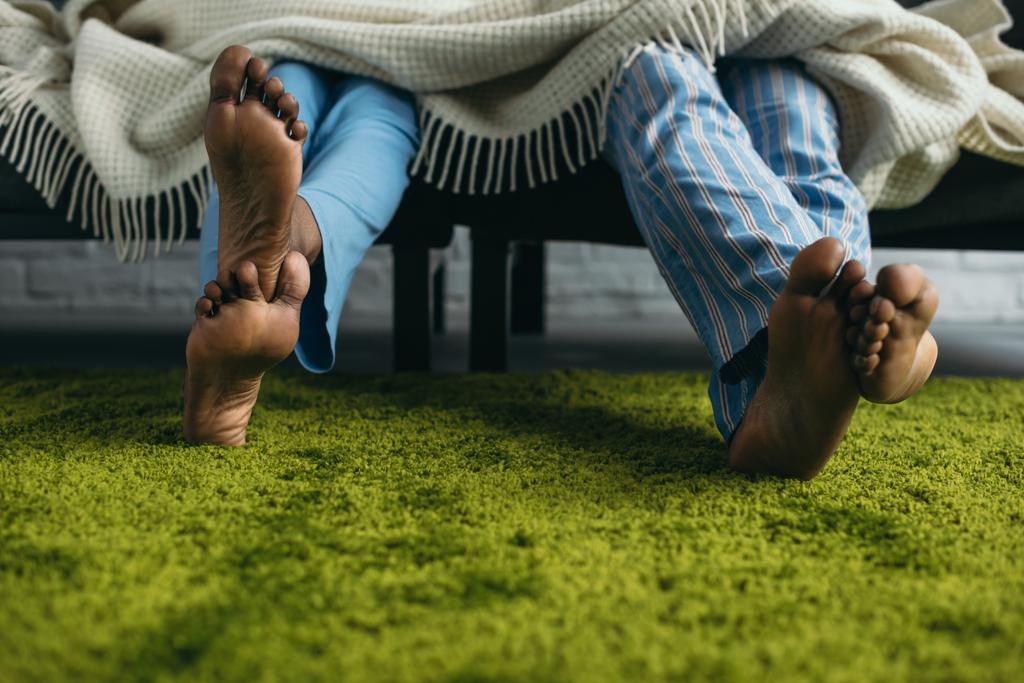 家で一緒に時間を過ごすパジャマで裸足のアフリカ系アメリカ人カップルのショットをトリミング - 写真・画像