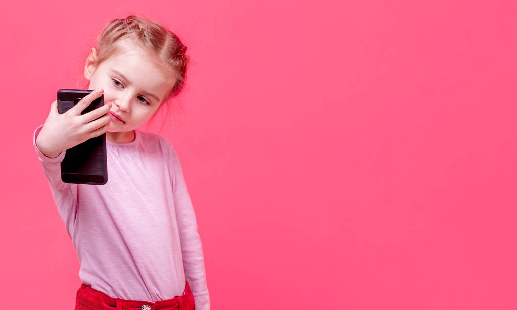 Pieni tyttö ottaa selfie edessä vaaleanpunainen seinä
 - Valokuva, kuva