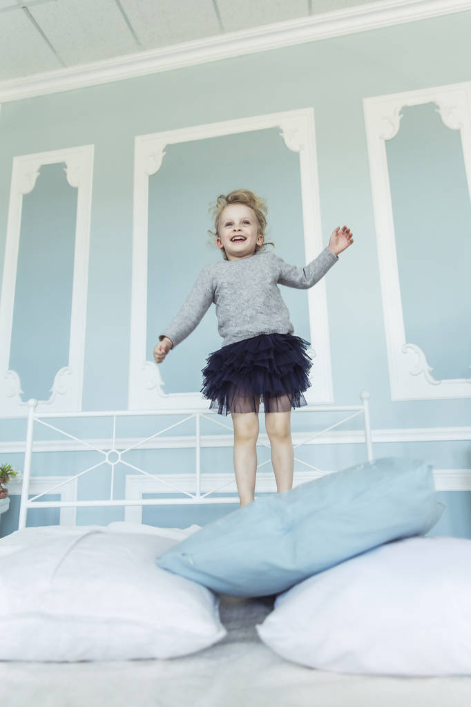 onnellista viisivuotias tyttö hyppää sängyllä
 - Valokuva, kuva