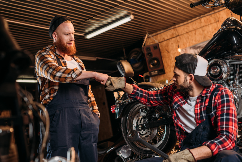 mecânica bonito fazendo bro punho na garagem de reparação de motocicleta
 - Foto, Imagem