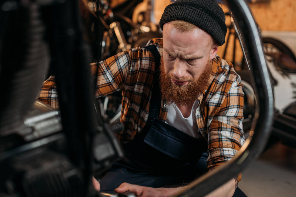 keskitetty korjaamo työntekijä vahvistamisesta moottoripyörän autotallissa
 - Valokuva, kuva