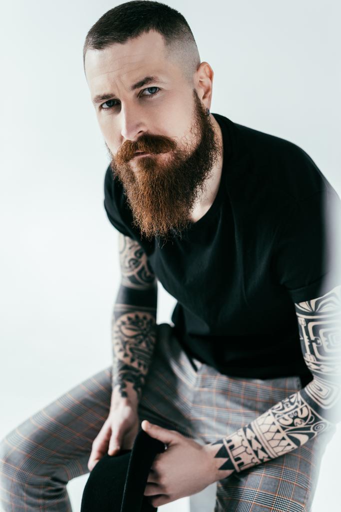 красивий бородатий татуйований чоловік дивиться на камеру на білому
 - Фото, зображення