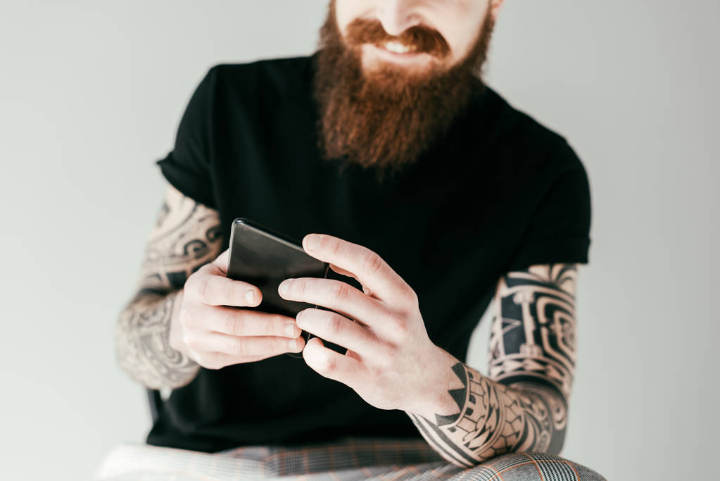 обрізане зображення бородатого татуйованого чоловіка за допомогою смартфона ізольовано на сірому
 - Фото, зображення