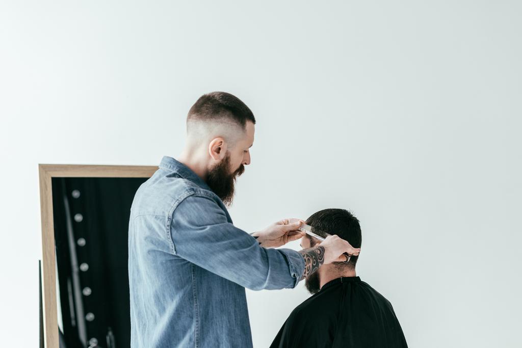 peluquero corte de pelo del cliente en la barbería aislado en blanco
 - Foto, Imagen