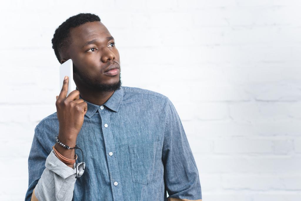 Hombre afroamericano hablando en smartphone por pared blanca
 - Foto, Imagen