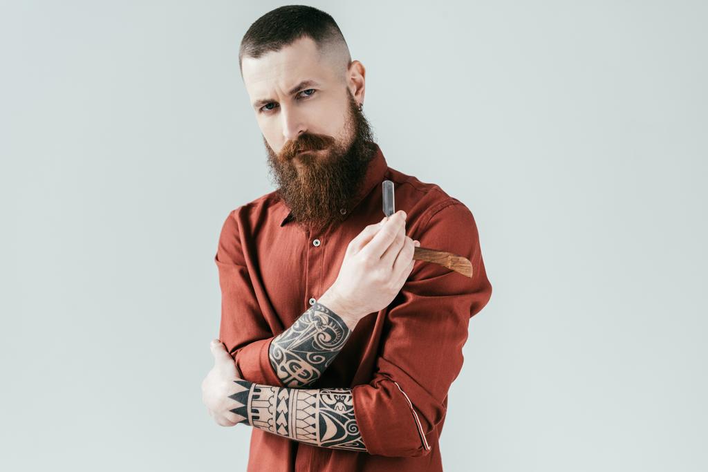 peluquero guapo serio que sostiene la navaja aislada en blanco
 - Foto, Imagen