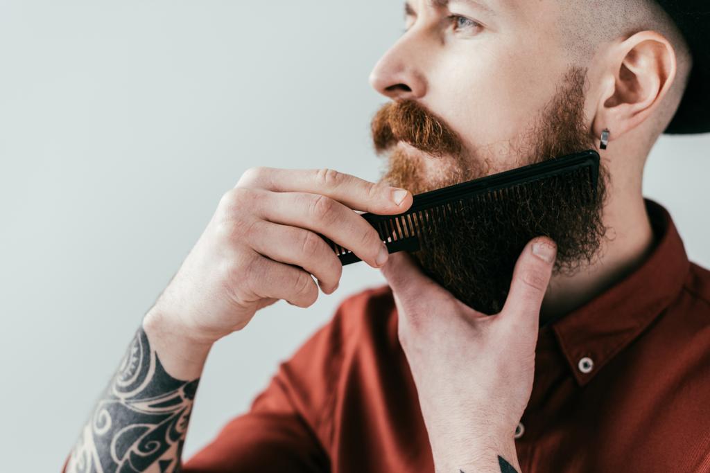 boční pohled Tetovaný muž česání vousy izolované na bílém - Fotografie, Obrázek