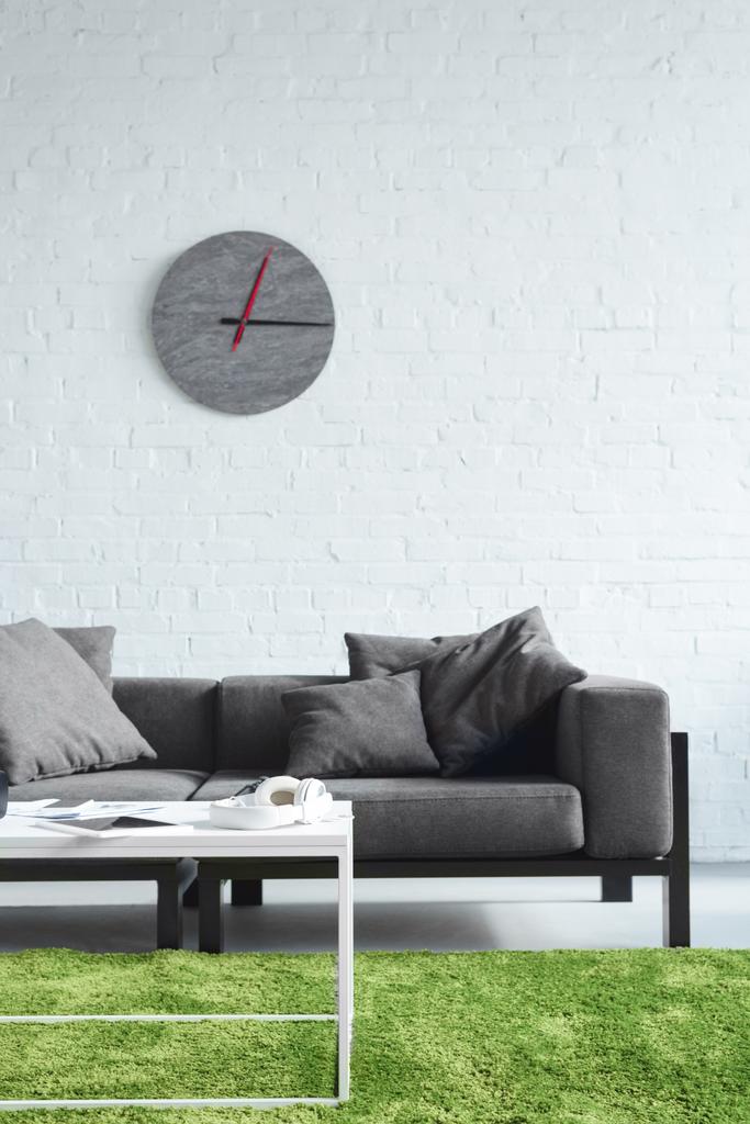 Kodikas sisustus moderni harmaa sohva ja kello seinällä
 - Valokuva, kuva