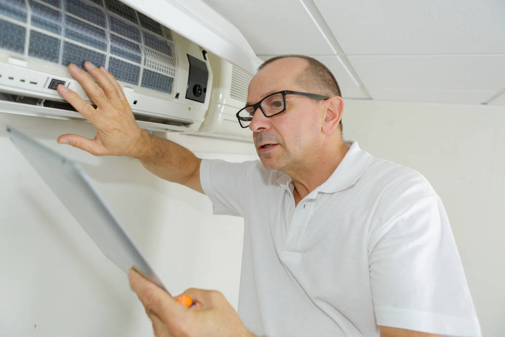 man met een tablet aan te passen airconditioningsysteem - Foto, afbeelding