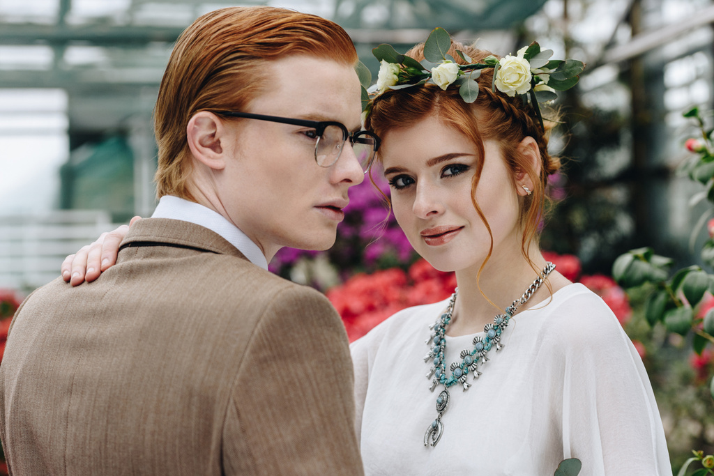 beautiful elegant young red-haired wedding couple standing together in botanical garden - Photo, Image
