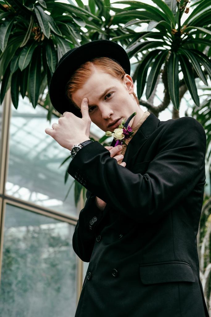 portrait of stylish young red hair man in hat in glasshouse   - Photo, Image