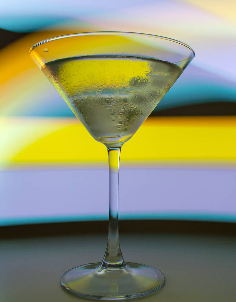 ein Martini-Glas mit einem Cocktail in schönem Licht in verschiedenen Farben - Foto, Bild