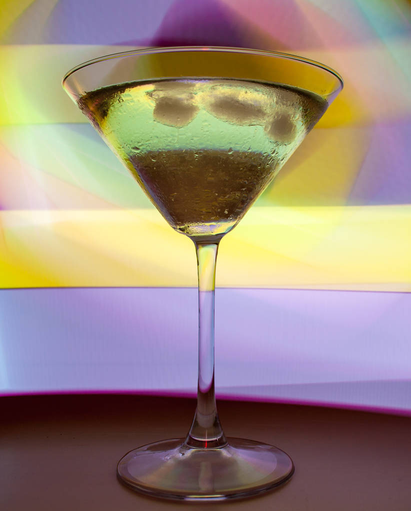 Бокал мартини с коктейлем в красивом свете разных цветов
 - Фото, изображение