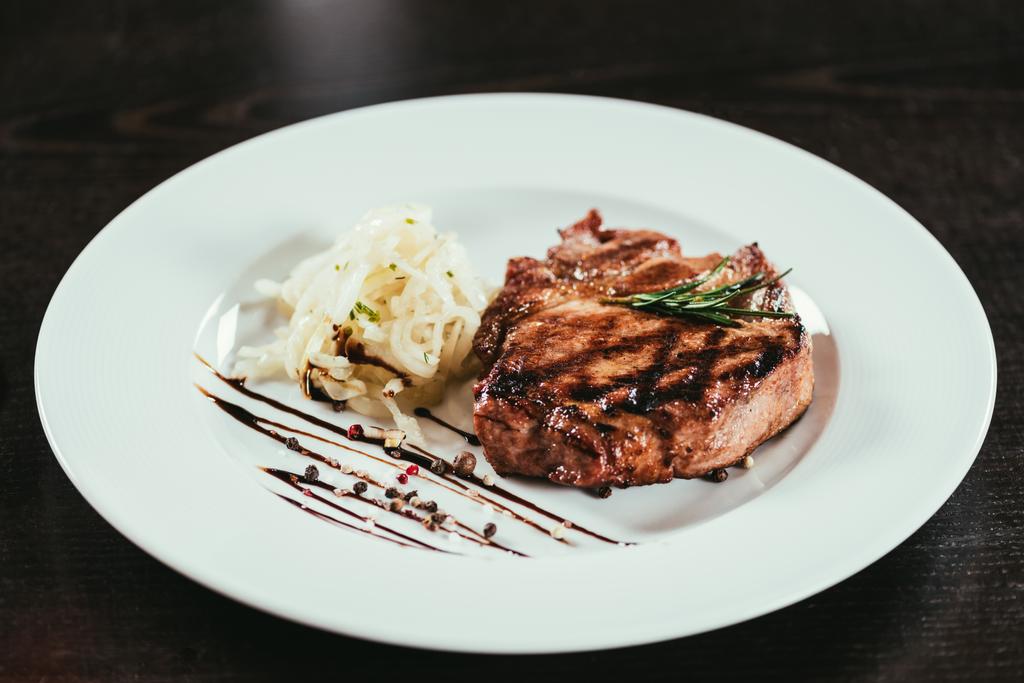 leckeres gegrilltes saftiges Steak mit Rosmarin und Sauce auf dem Teller  - Foto, Bild