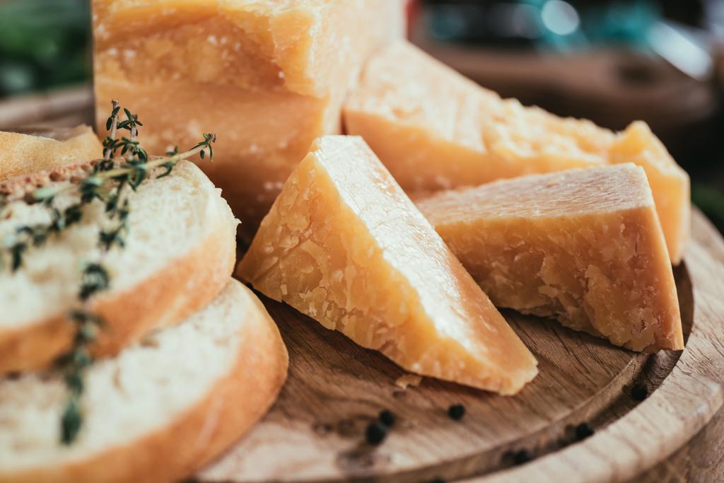 Close-up beeld van heerlijke Parmezaanse kaas en de moten van vers stokbrood op houten snijplank  - Foto, afbeelding