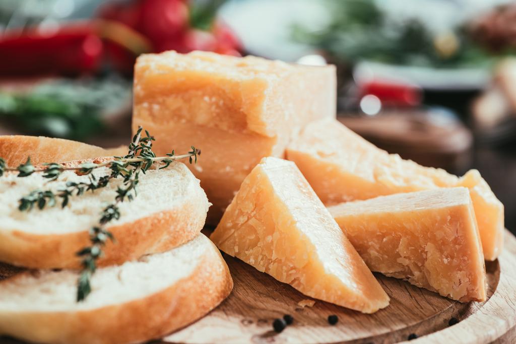 dilimlenmiş baget ve lezzetli parmesan peyniri yakından görmek ahşap kesme tahtası üzerinde - Fotoğraf, Görsel