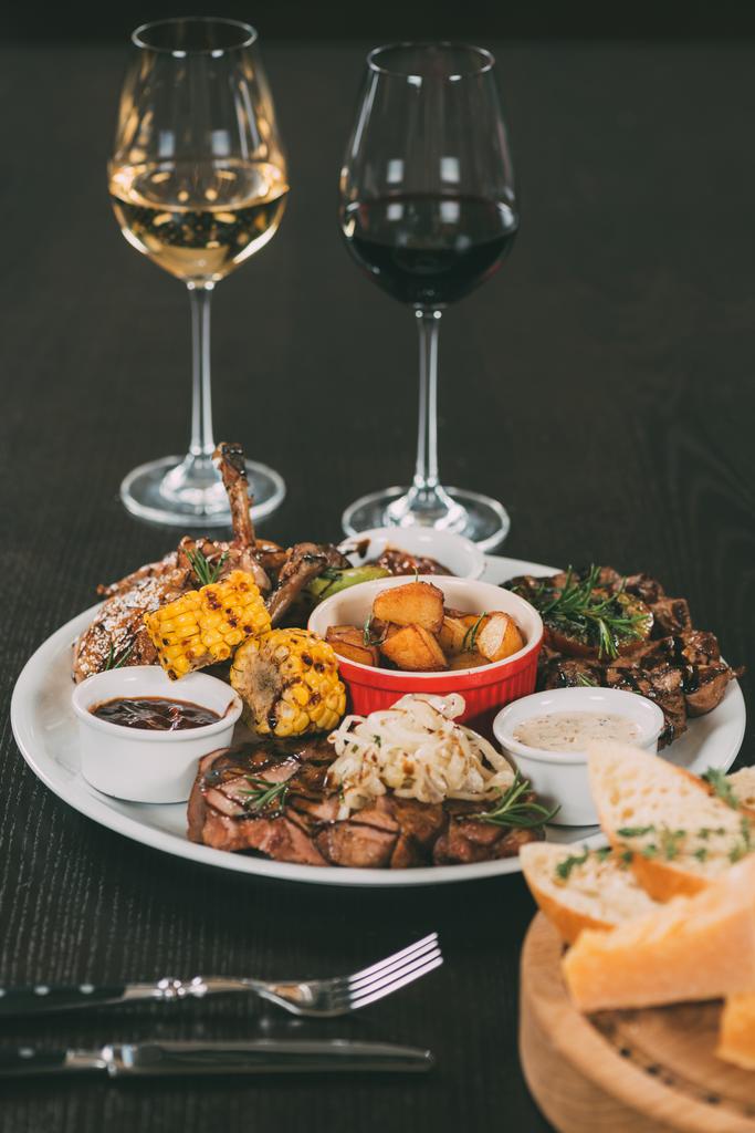 szklanki wina i płyta z grillowanymi warzywami i mięsem na stole w restauracji  - Zdjęcie, obraz