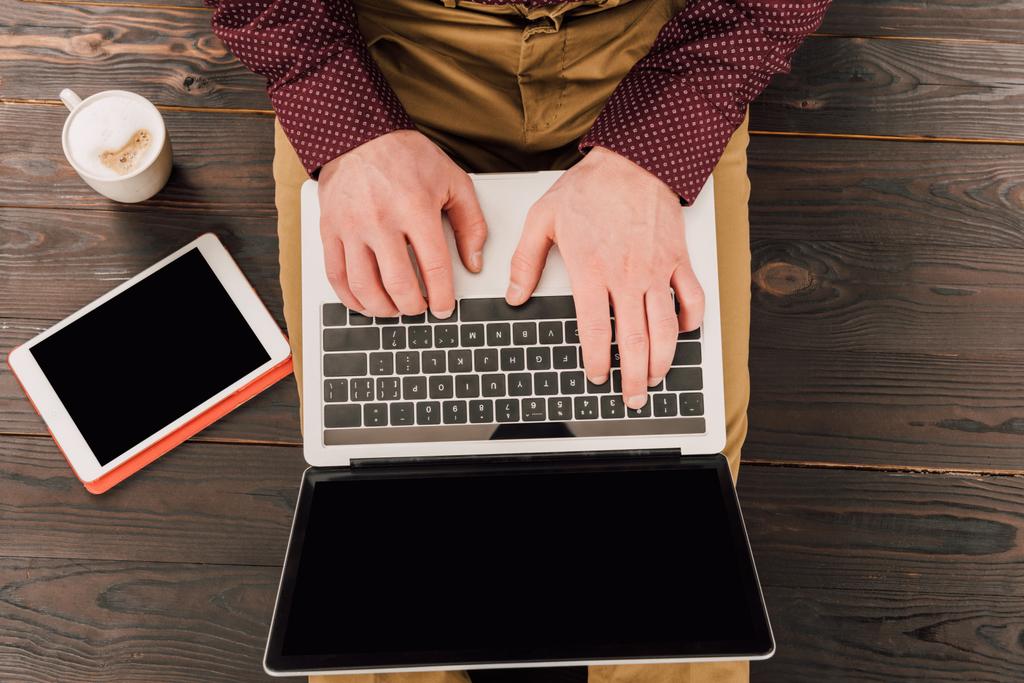 Вид сверху на бизнесмена, сидящего за цифровым столом, чашкой кофе и ноутбуком с экраном для Blank
 - Фото, изображение
