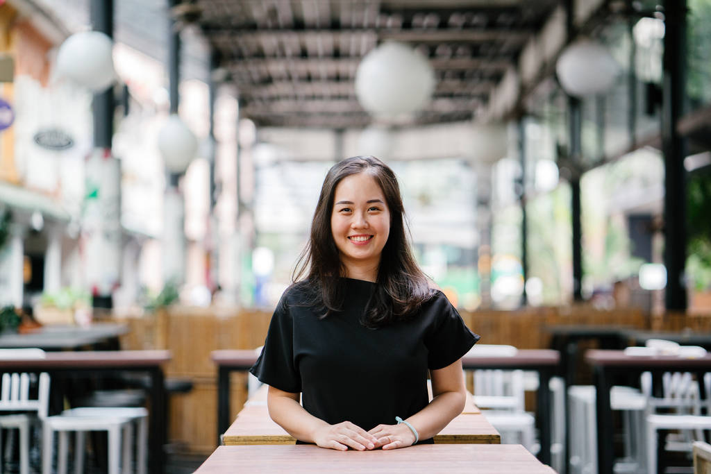 o gün boyunca Asya'da bir şehirde bir restoranda bir tablo üzerinde eğilir iken genç ve çekici Çinli Asyalı kadın gülümsüyor. O akıllı rahat giyinmiş ve rahat ve mutlu. - Fotoğraf, Görsel