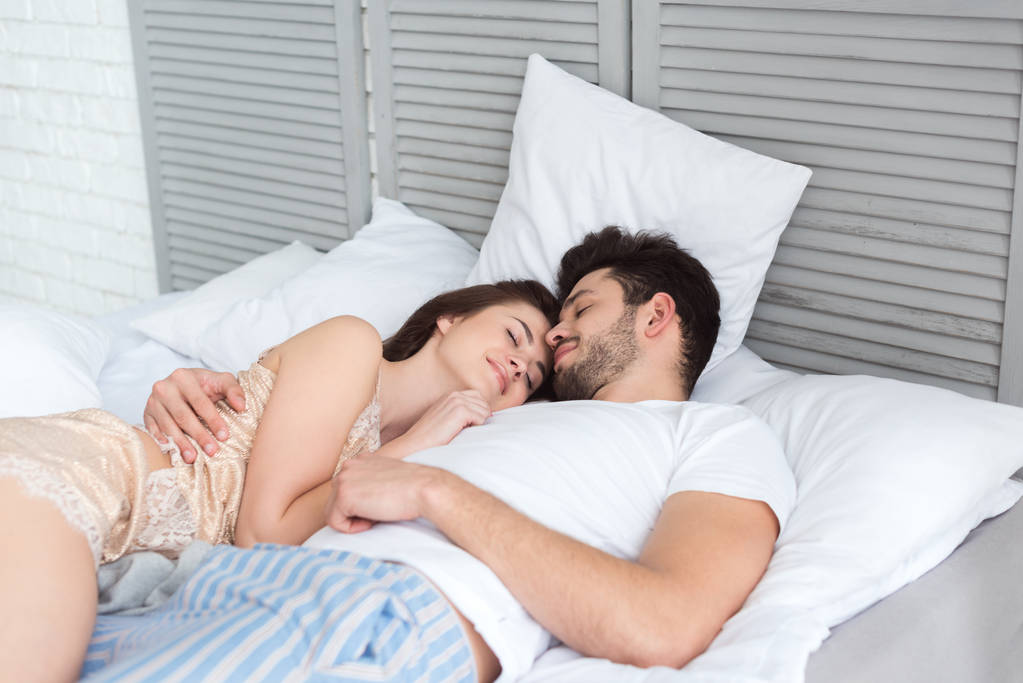 mladý pár v pyžamu spolu spí v posteli - Fotografie, Obrázek