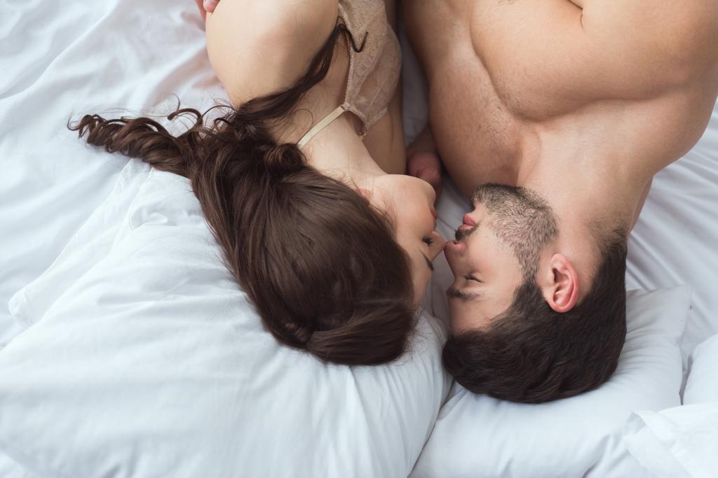 overhead view of young sexy couple lying on bed together at home - Photo, Image