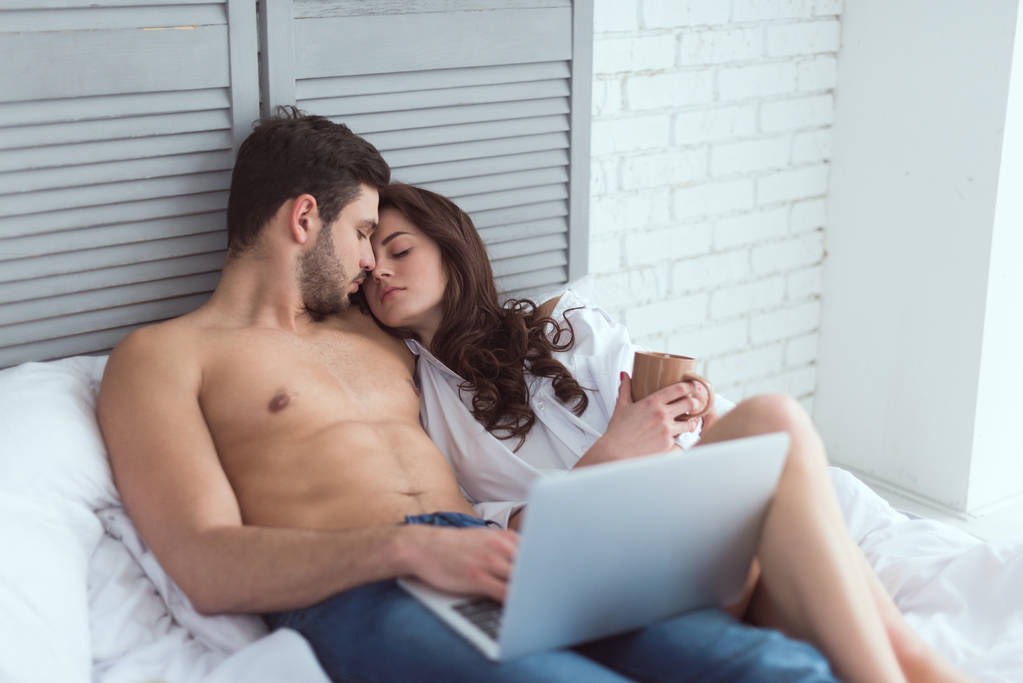 jovem casal com laptop descansando na cama em casa
 - Foto, Imagem