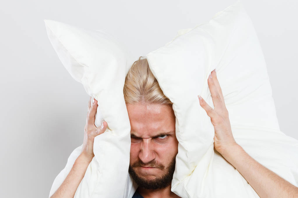 Θυμωμένος άνθρωπος, κλείνοντας τα αυτιά με μαξιλάρια - Φωτογραφία, εικόνα