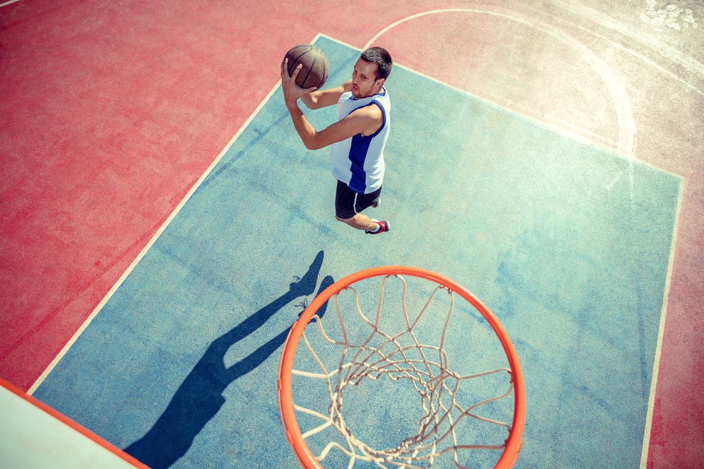 Άποψη υψηλής γωνίας του καλαθοσφαιριστή dunking μπάσκετ στο στεφάνι - Φωτογραφία, εικόνα
