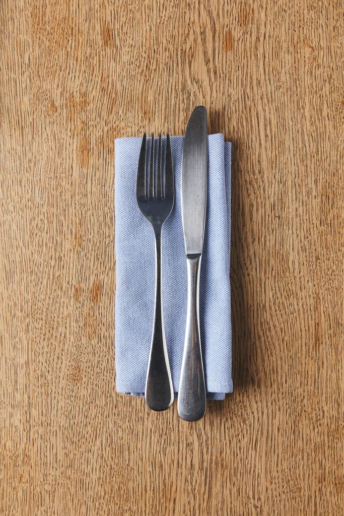 Fork and knife on napkin on wooden table - Photo, Image
