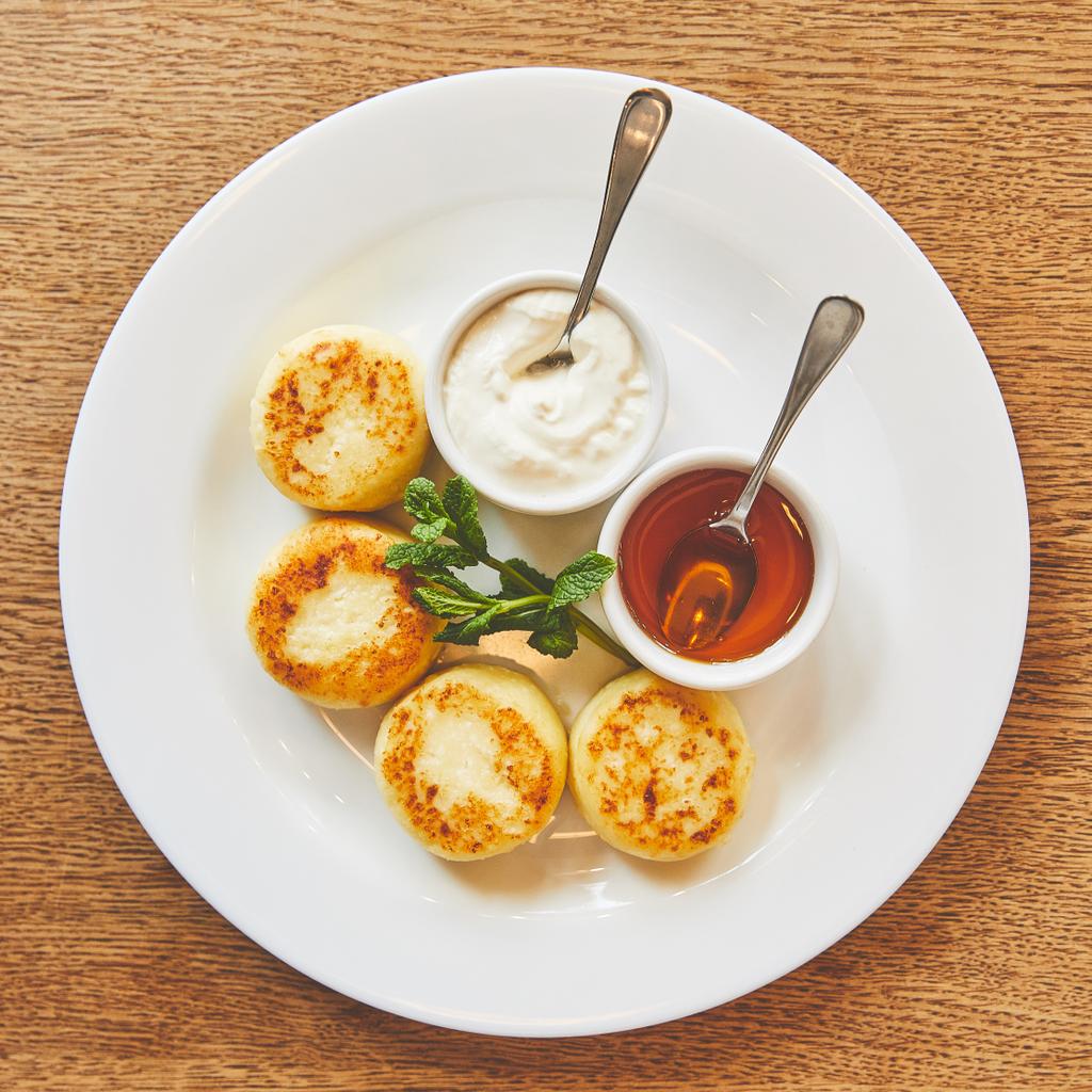 Gebakken kaas pannenkoeken schotel geserveerd met honing en zure room - Foto, afbeelding