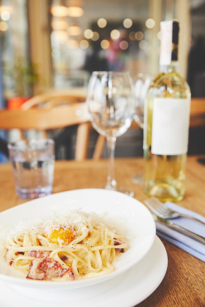 Vergrote weergave van de pasta carbonara in witte plaat geserveerd met witte wijn - Foto, afbeelding