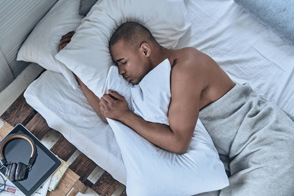 κάτοψη του νεαρού άνδρα αφρικανική στον ύπνο στο κρεβάτι στο σπίτι               - Φωτογραφία, εικόνα