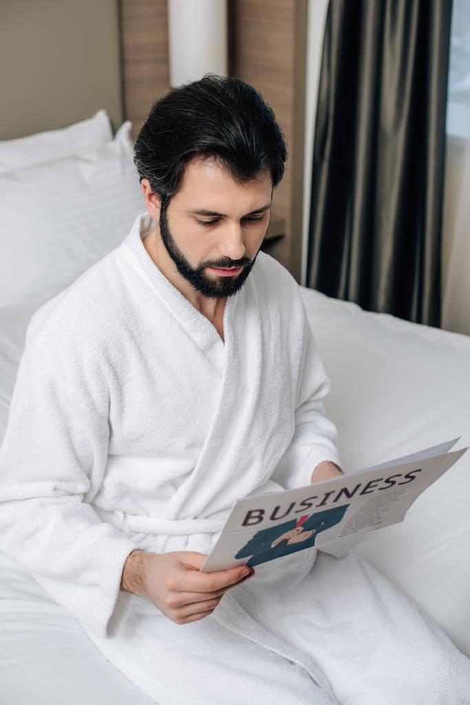 Seriöser Geschäftsmann im Bademantel liest Zeitung in Hotelsuite - Foto, Bild