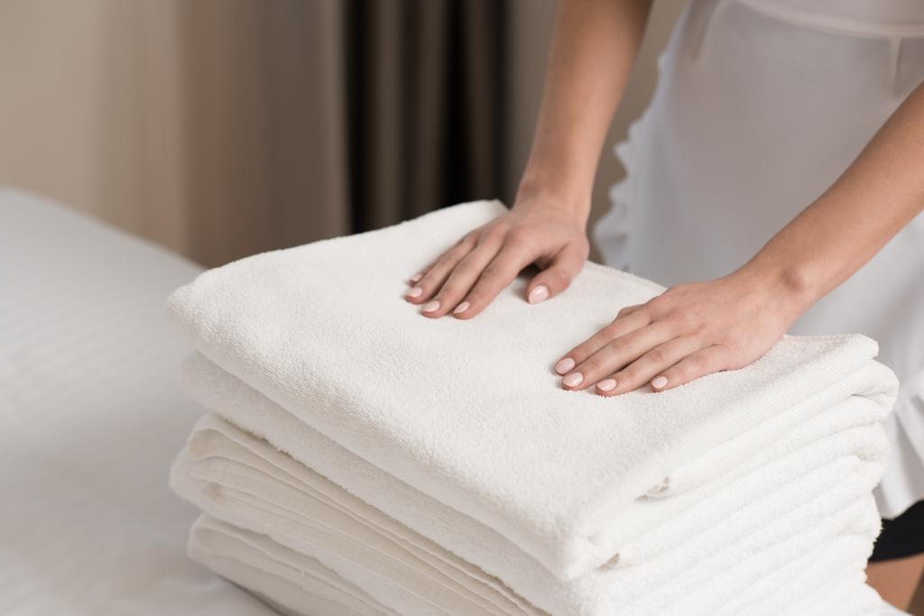 jovem bela empregada doméstica em uniforme com pilha de toalhas limpas
 - Foto, Imagem
