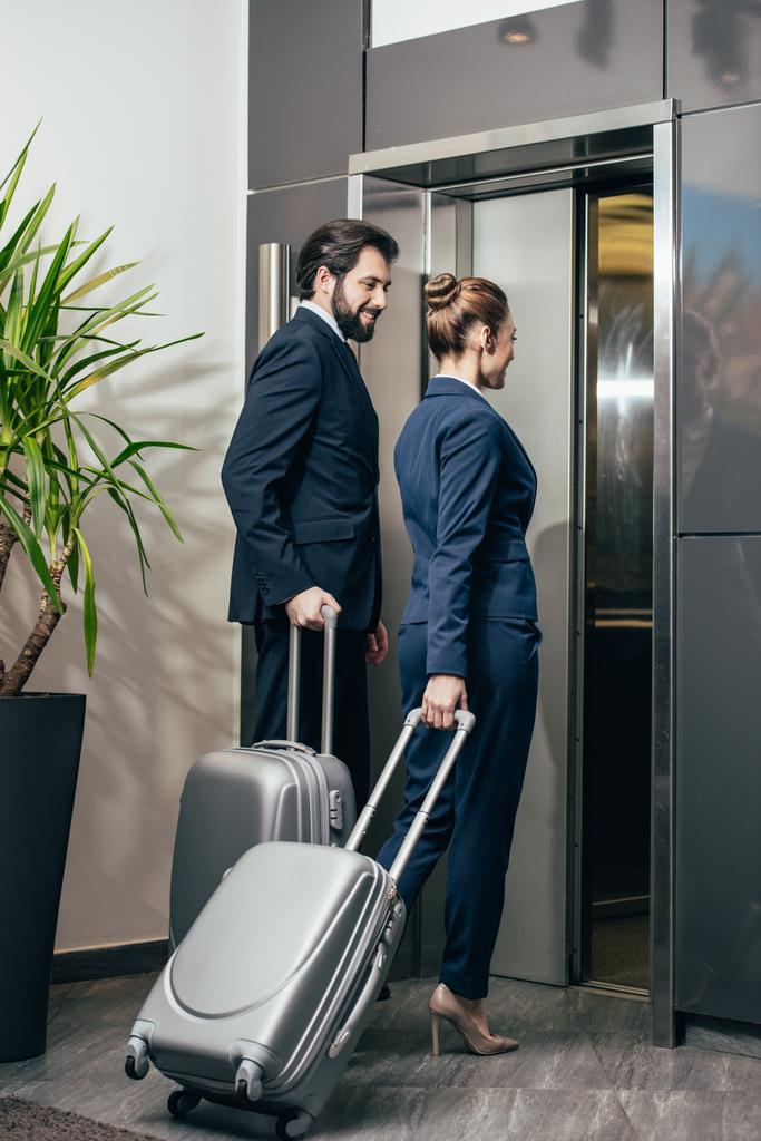 бизнесмены с багажом входят в лифт вместе
 - Фото, изображение