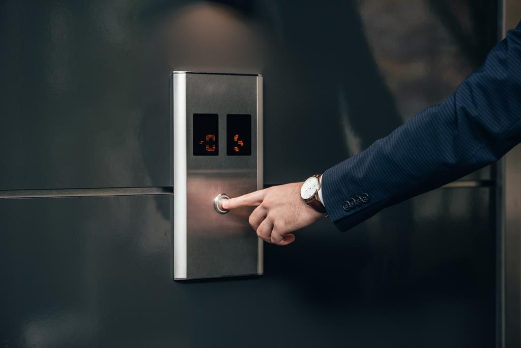 rajattu laukaus liikemies puku painamalla painiketta hissin
 - Valokuva, kuva