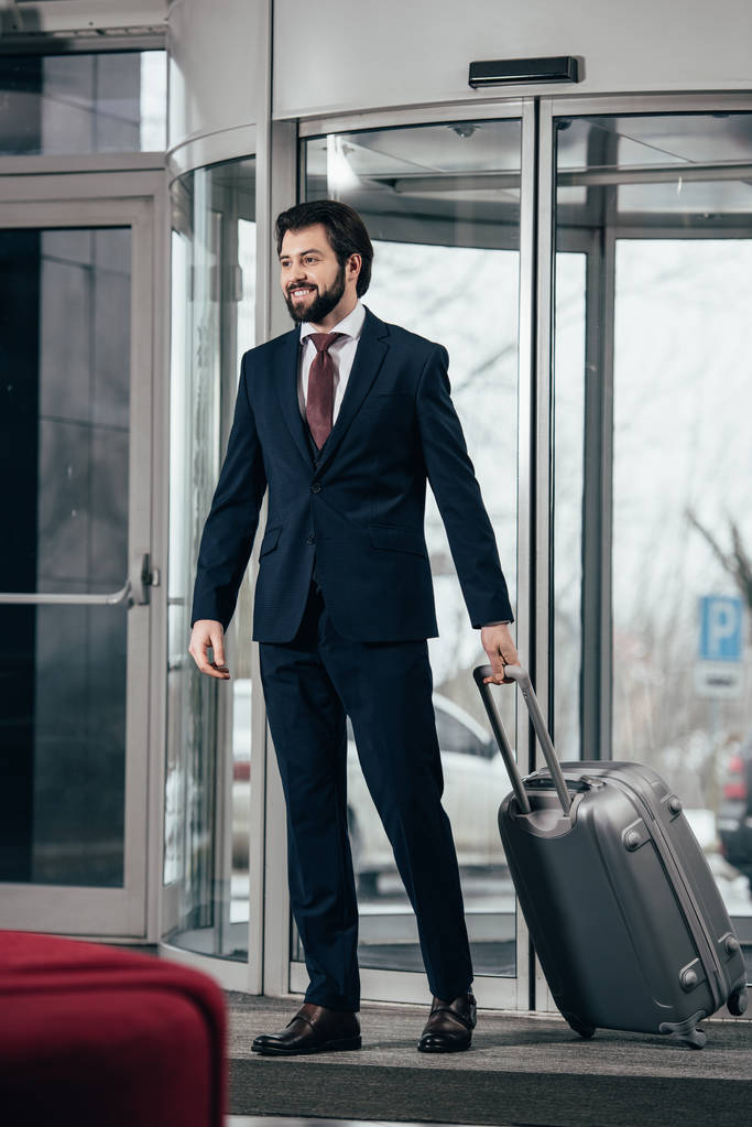 homem de negócios bonito com bagagem saindo do hotel
 - Foto, Imagem