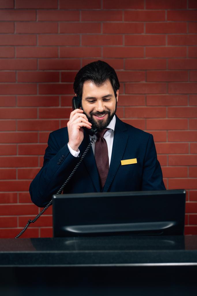 Ξενοδοχείο ρεσεψιονίστ λήψη τηλεφωνικής κλήσης στον εργασιακό χώρο - Φωτογραφία, εικόνα