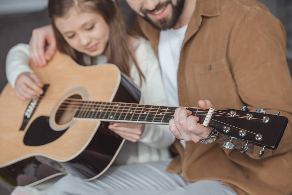 imagem recortada de pai ensinando filha tocando guitarra acústica
 - Foto, Imagem